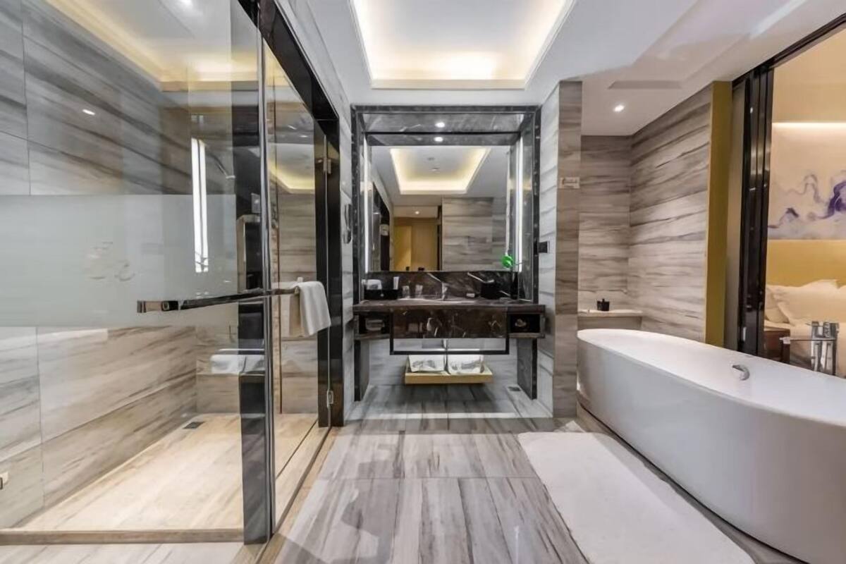 A modern bathroom with a glass shower enclosure, a freestanding bathtub, and a marble vanity.