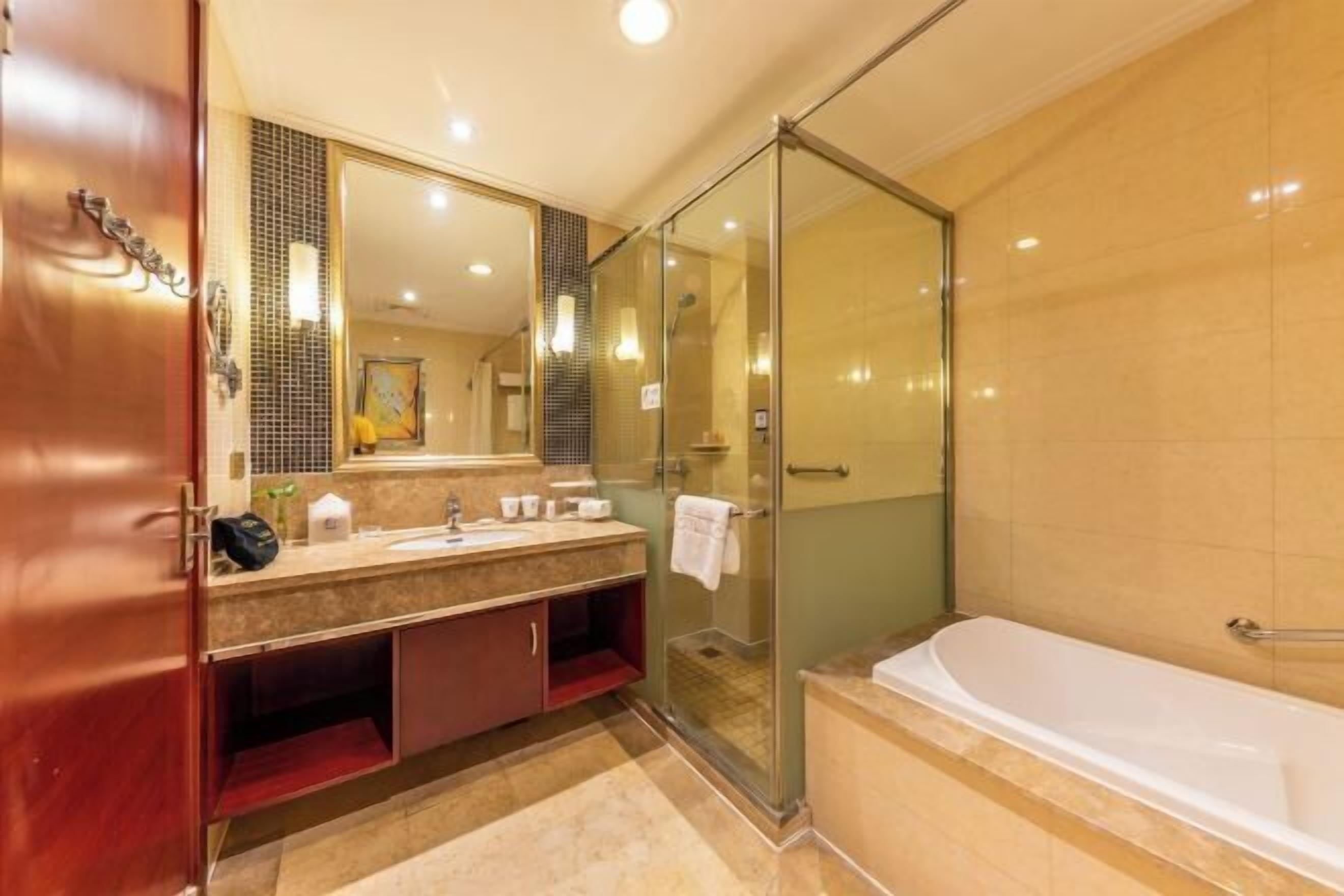 A bathroom with a glass shower enclosure, a bathtub, and a vanity with a mirror.