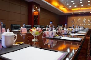 Un salón de conferencias con una larga mesa dispuesta para una reunión, tarjetas de identificación y un centro de mesa decorativo.