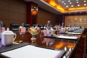 Un salón de conferencias con una larga mesa dispuesta para una reunión, tarjetas de identificación y un centro de mesa decorativo.