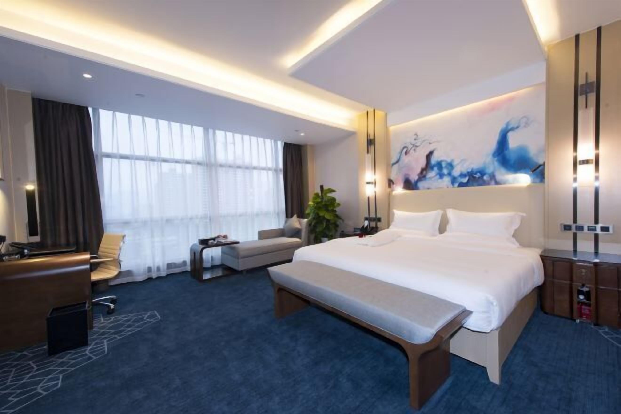 Una habitación de hotel moderna con una cama grande, un escritorio y una zona de estar.