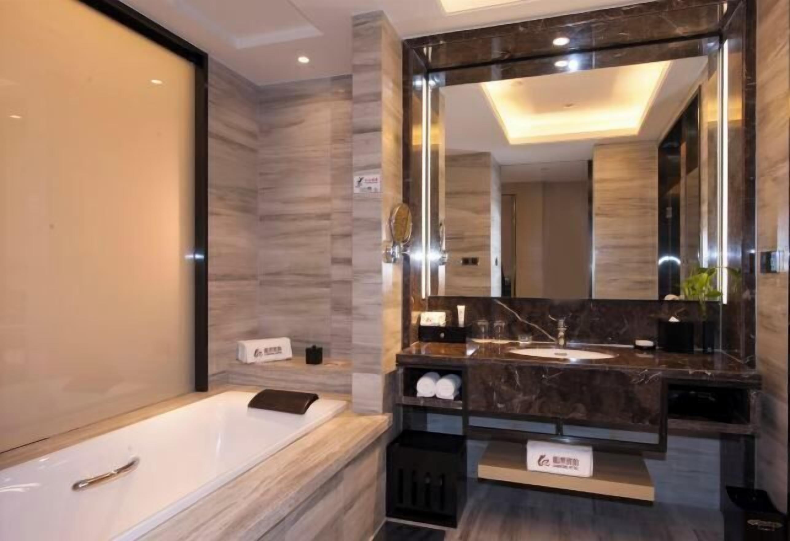 Un baño moderno con un espejo grande, una bañera y un tocador con lavamanos.
