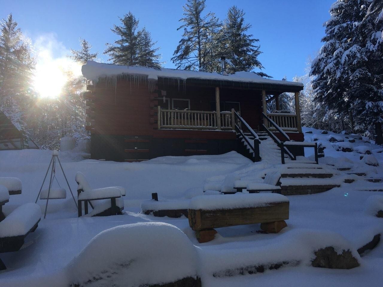 A cabin with a wooden deck and a staircase leading to the entrance.