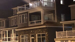 Un edificio residencial de varios pisos con balcones, garaje y fachada de piedra.