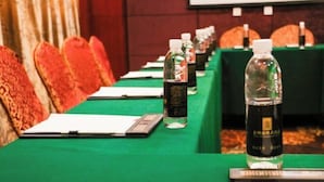 Uma sala de conferências com uma mesa comprida, cadeiras e garrafas de água.