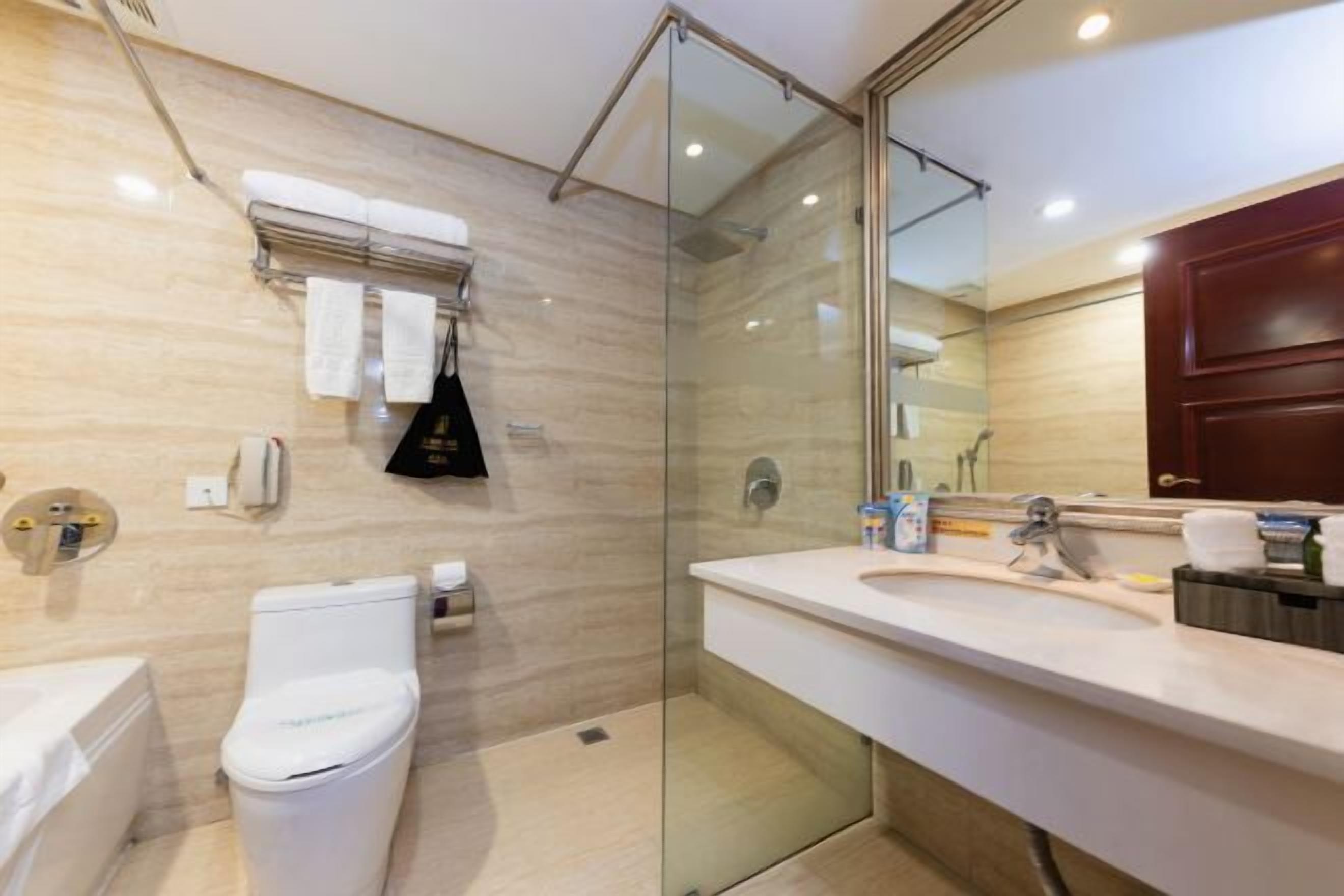 A modern bathroom with a glass-enclosed shower, a white toilet, a sink with a mirror, and a towel rack.