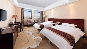 Quarto de hotel com duas camas, uma escrivaninha, uma cadeira, televisão e vista para a cidade.