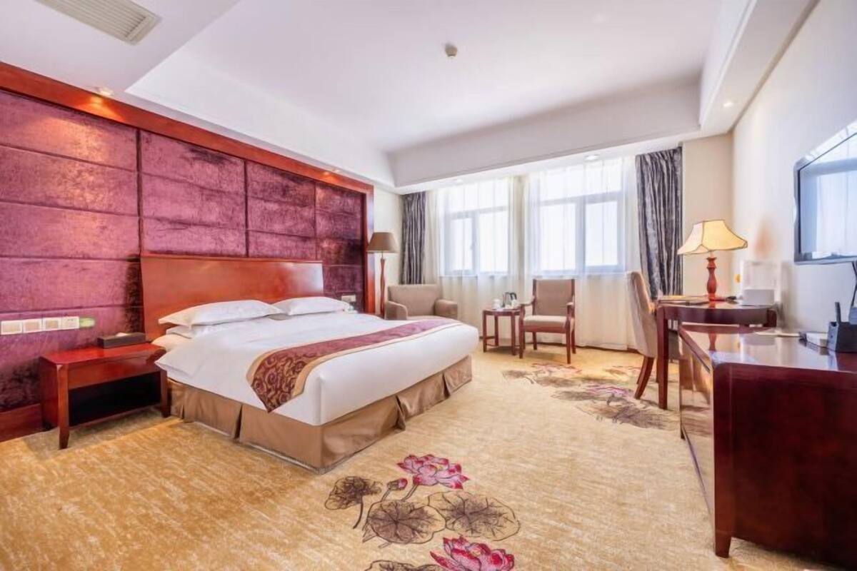 Una habitación de hotel con una cama grande, un escritorio, una silla y un televisor.