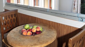 A round wooden table with a glass bowl containing various fruits, positioned near a window with a view of buildings. - Sur Hotel Sultanahmet (Istanbul)