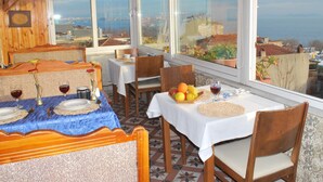 A dining area with tables set for two, a view of the sea, and a tiled floor. - Sur Hotel Sultanahmet (Istanbul)