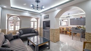 A spacious living area with a sofa, coffee table, and a television. There is a kitchen area with cabinets and a dining table. - Sur Hotel Sultanahmet (Istanbul)