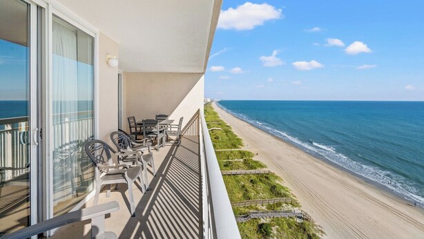 A balcony with outdoor furniture overlooking a beach. - Clean Bright Oceanfront Condo, Jacuzzi Tub, Pools | Crescent Shores - N 1403 (North Myrtle Beach)