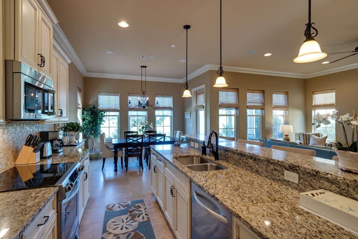 A spacious kitchen with granite countertops, stainless steel appliances, and pendant lighting.