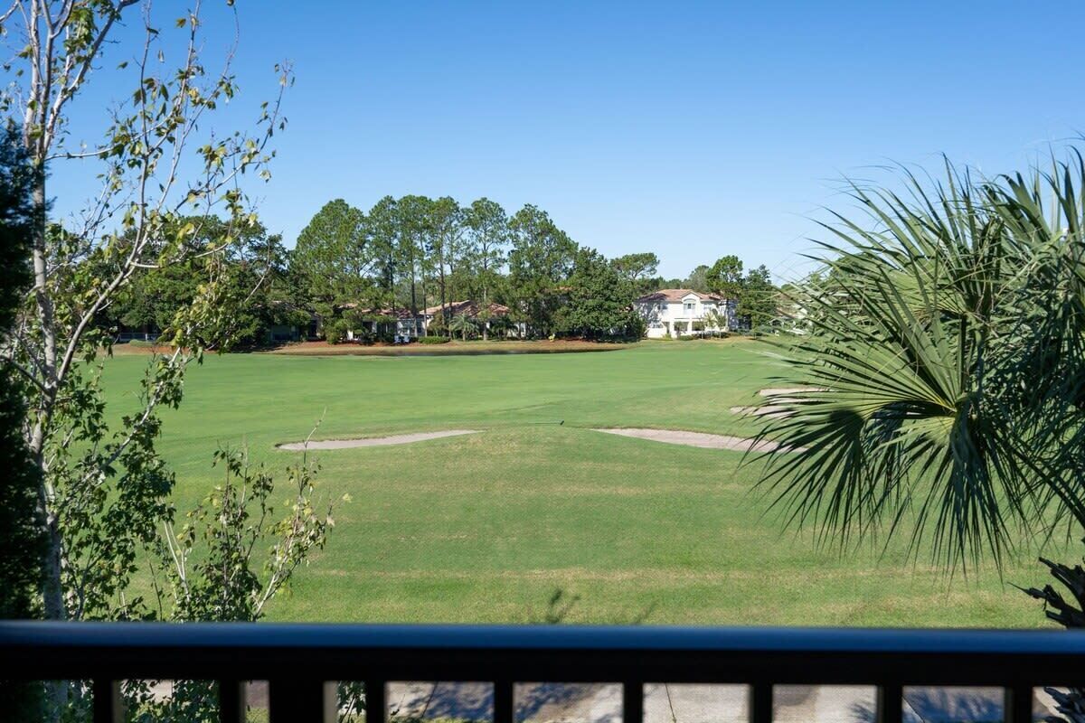 A golf course with a clear view of the green, sand bunkers, and surrounding trees.