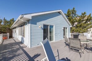 A small, light blue house with a covered patio area featuring a table and chairs.