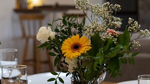 Una mesa de comedor con un jarrón de flores, platos y vasos.