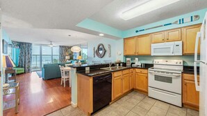 A modern kitchen with wooden cabinets, a built-in dishwasher, and a white stove. - Upscale Oceanfront Condo, Lazy River, BBQ Grill | Crescent Shores - S 107 (North Myrtle Beach)