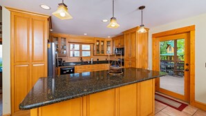 A spacious kitchen with wooden cabinets, granite countertops, and pendant lighting. - Near Asheville, near the stars, nearly perfect!  Almost Heaven.  3000 ft. (Old Fort)