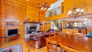 A spacious living room with a fireplace, leather sofa, wooden dining table, and a television. - Near Asheville, near the stars, nearly perfect!  Almost Heaven.  3000 ft. (Old Fort)