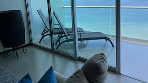 Ein modernes Zimmer mit einer großen Glasschiebetür, die auf einen Balkon mit Meerblick führt.