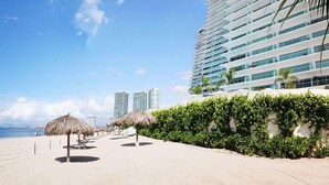 Ein Hotel direkt am Strand mit modernem Design, ein langes Gebäude mit horizontalen Fenstern und heller Fassade.