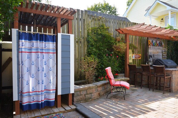 A patio area with a wooden pergola, a barbecue station, and a red chair.