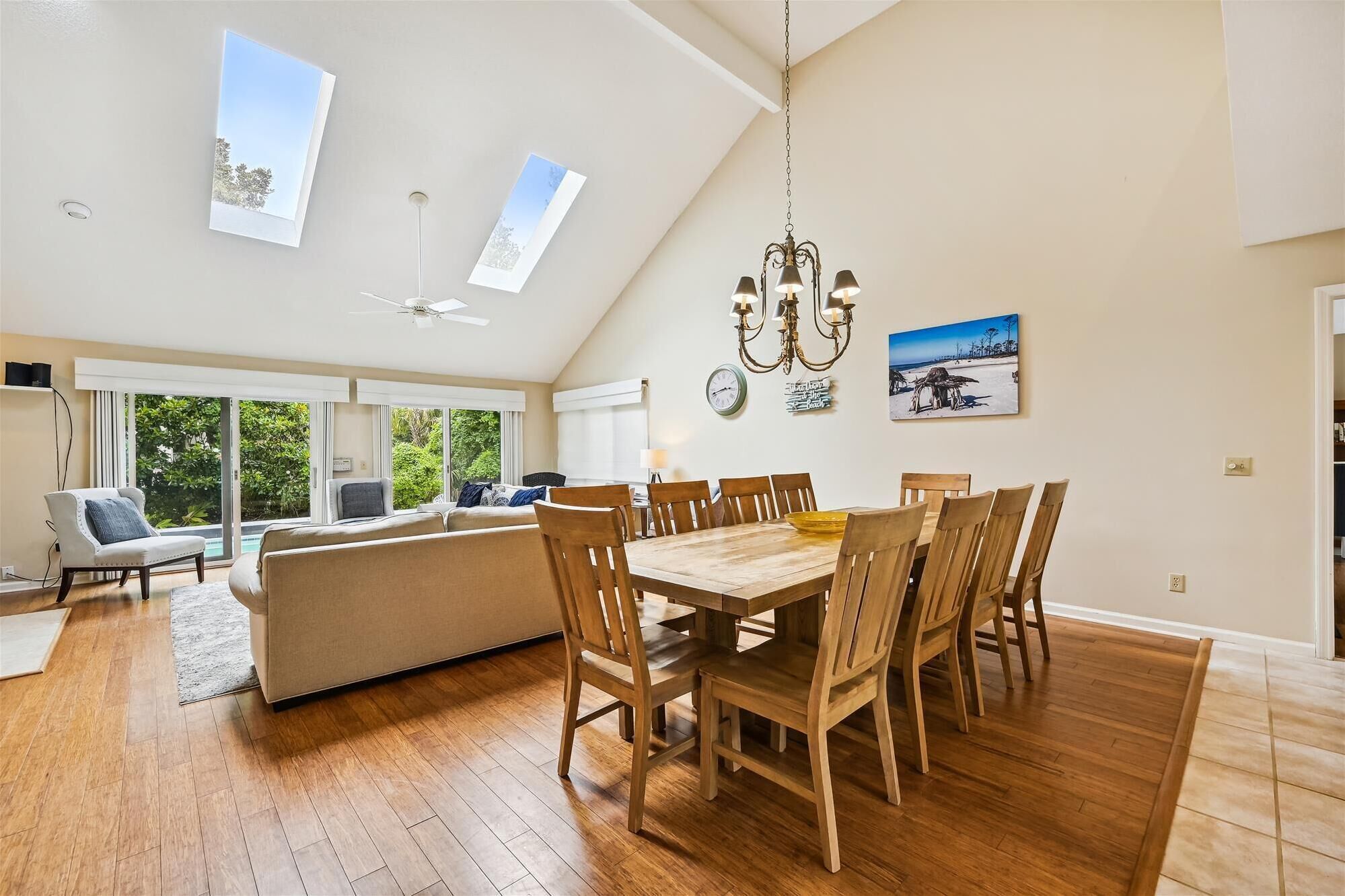 A spacious living area with a dining table, multiple chairs, a sofa, and a ceiling fan.