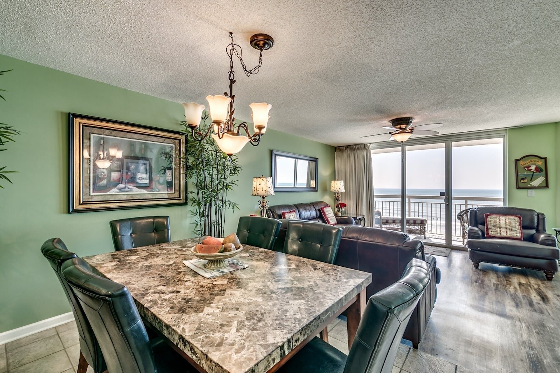 A spacious dining area with a marble table, leather chairs, and a ceiling fan.