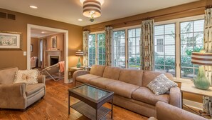 Una sala de estar con un sofá color beige, una mesa de centro de vidrio y una chimenea.