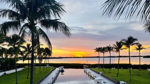 A marina with boats docked, surrounded by palm trees and a calm water body reflecting the sunset. - Waterfront luxury Villa (43) with spectacular sunset views and boat slip (Marathon)