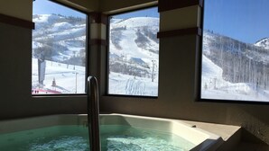 A spa area with a hot tub and a view of a snowy mountain landscape through large windows.