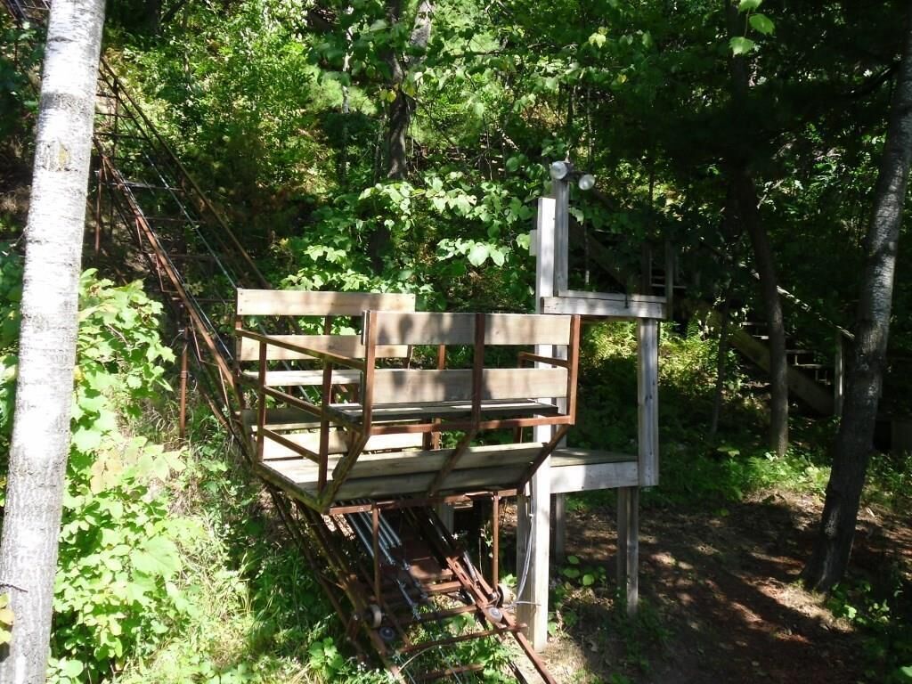 Een houten bank in een bebost gebied, met een metalen constructie en een bord.
