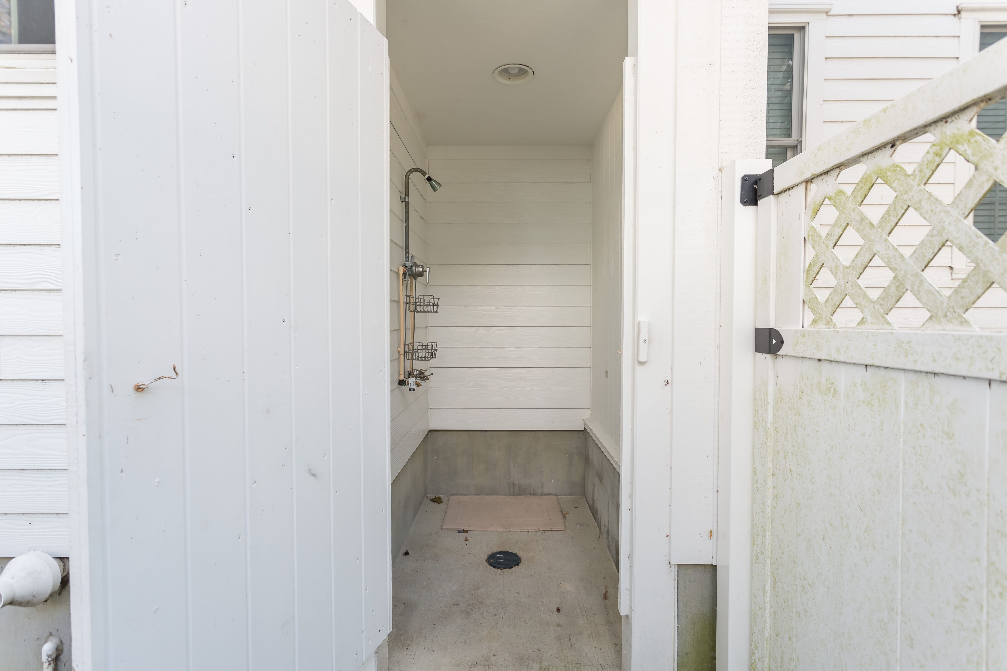 Ein schmales, abgeschlossenes Badezimmer mit Dusche, kleinem Waschbecken und Toilette.