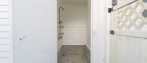 Ein schmales, abgeschlossenes Badezimmer mit Dusche, kleinem Waschbecken und Toilette.
