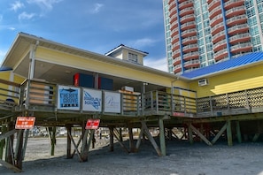 A pier with signs for Cherry Grove Pier, Cardwalk Beach Cafe, and Prince Resort.