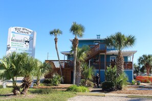 Un bien immobilier situé en bord de mer, avec une enseigne indiquant « Magasin de plage et de surf » et « T-shirts ».