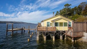 Ein Haus auf Stelzen über dem Wasser mit einem Steg, umgeben von Bäumen.