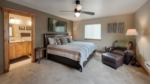 Une chambre à coucher comprenant un lit, une chaise, un bureau, un ventilateur de plafond et une fenêtre.