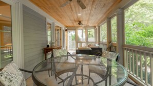 A glass-top dining table with chairs, a ceiling fan, and a view of greenery outside. - Beautiful 4BR Rehoboth Beach Home w/ Gorgeous Porch (Rehoboth Beach)