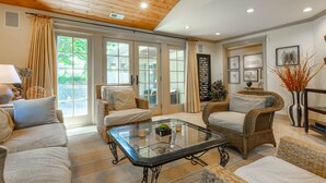 A spacious living room with a high ceiling, wicker furniture, and a glass coffee table. - Beautiful 4BR Rehoboth Beach Home w/ Gorgeous Porch (Rehoboth Beach)