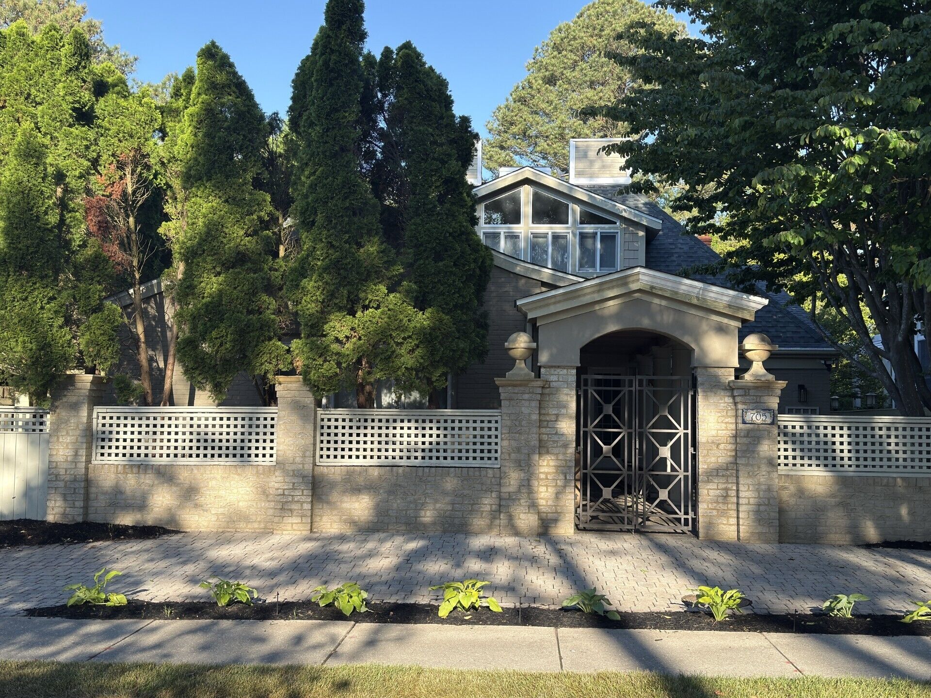 A residential house with a stone facade, a gated entrance, and a brick pathway.