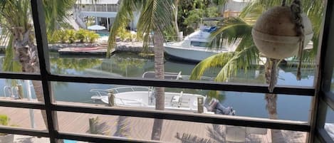 A view of a marina with boats docked, palm trees, and a building with a balcony.
