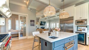A modern kitchen with a central island, stainless steel appliances, and pendant lighting. - Luxury Ocean Blvd.  POOL/HOT TUB, PUTTING GREEN, ROOF TOP (Isle of Palms)