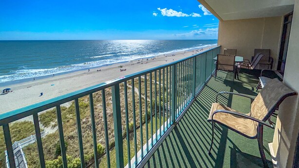 A balcony with a view of a beach and ocean.