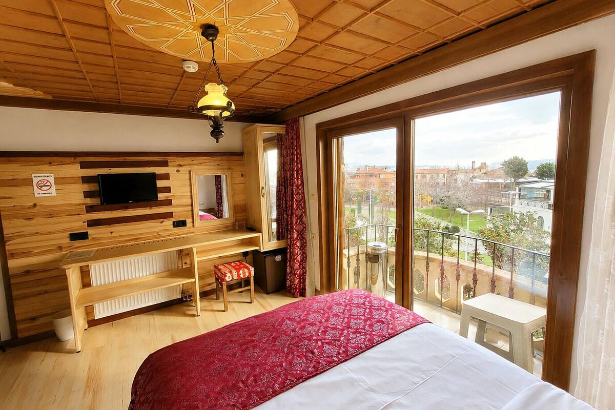 Une chambre à coucher avec un lit, une télévision, un bureau, un miroir et un balcon avec vue.