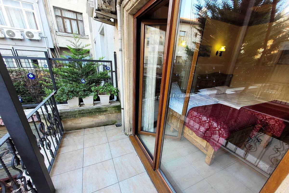 Un balcon avec un sol carrelé, un banc en bois et des plantes en pot.