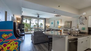A modern kitchen with a central island, a dining area with a view, and a living room with a large window. - Amazing 2BR Shores of Panama #213 | Remodeled Luxury Beachfront Condo | Same-Floor Reserved Parking (Panama City Beach)