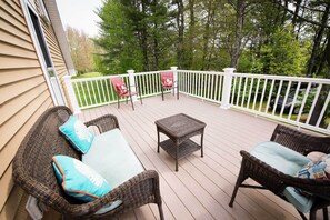 Une terrasse extérieure couverte, aménagée avec des meubles en osier et une petite table.