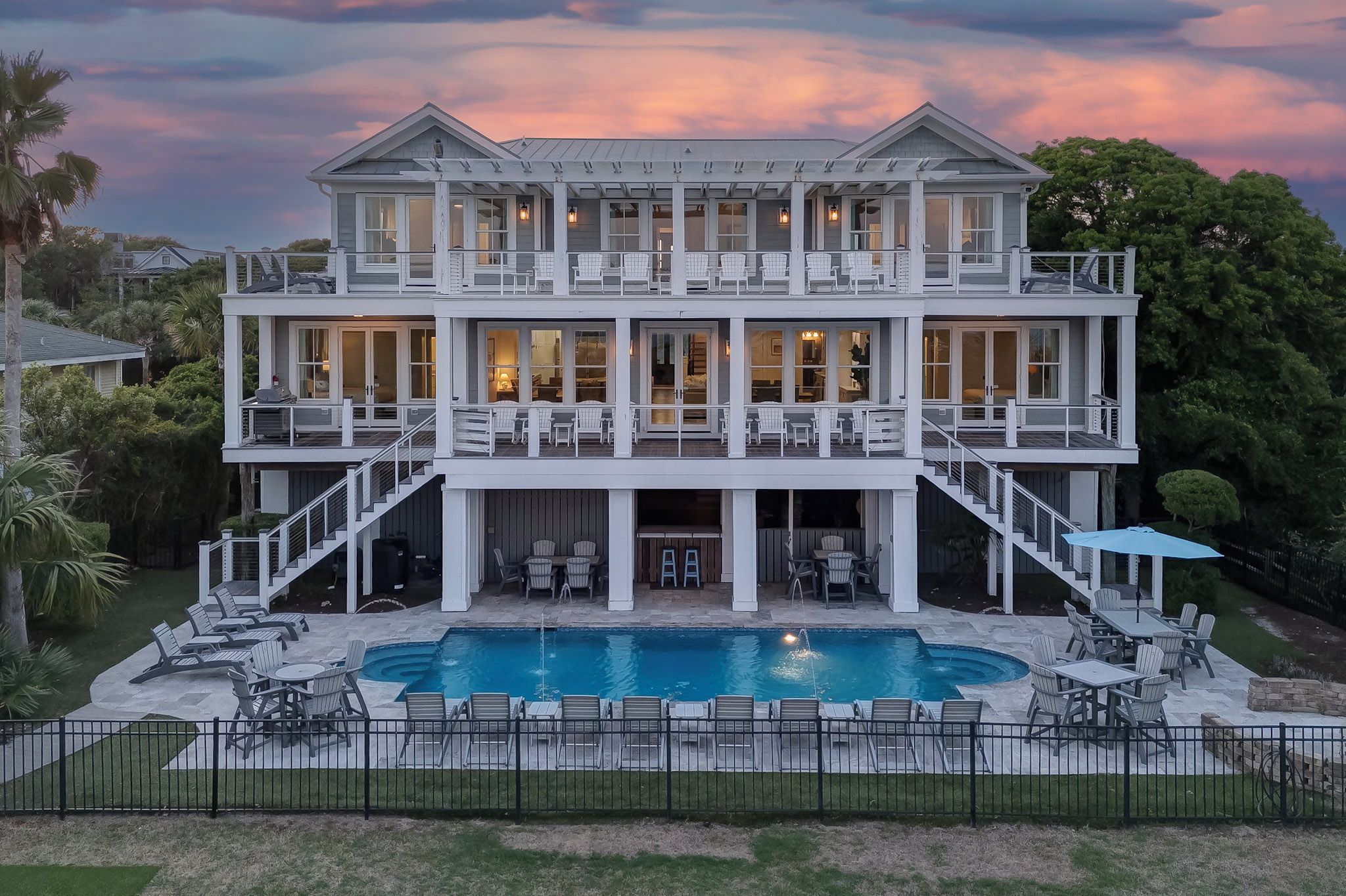 A two-story house with a large front porch, a swimming pool, and outdoor seating.
