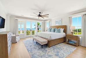 A bedroom with a large bed, a ceiling fan, a nightstand, a dresser, and a view of the ocean. - Port of Call on Isle of Palms OCEAN FRONT, Pool, boardwalk, putting green (Isle of Palms)